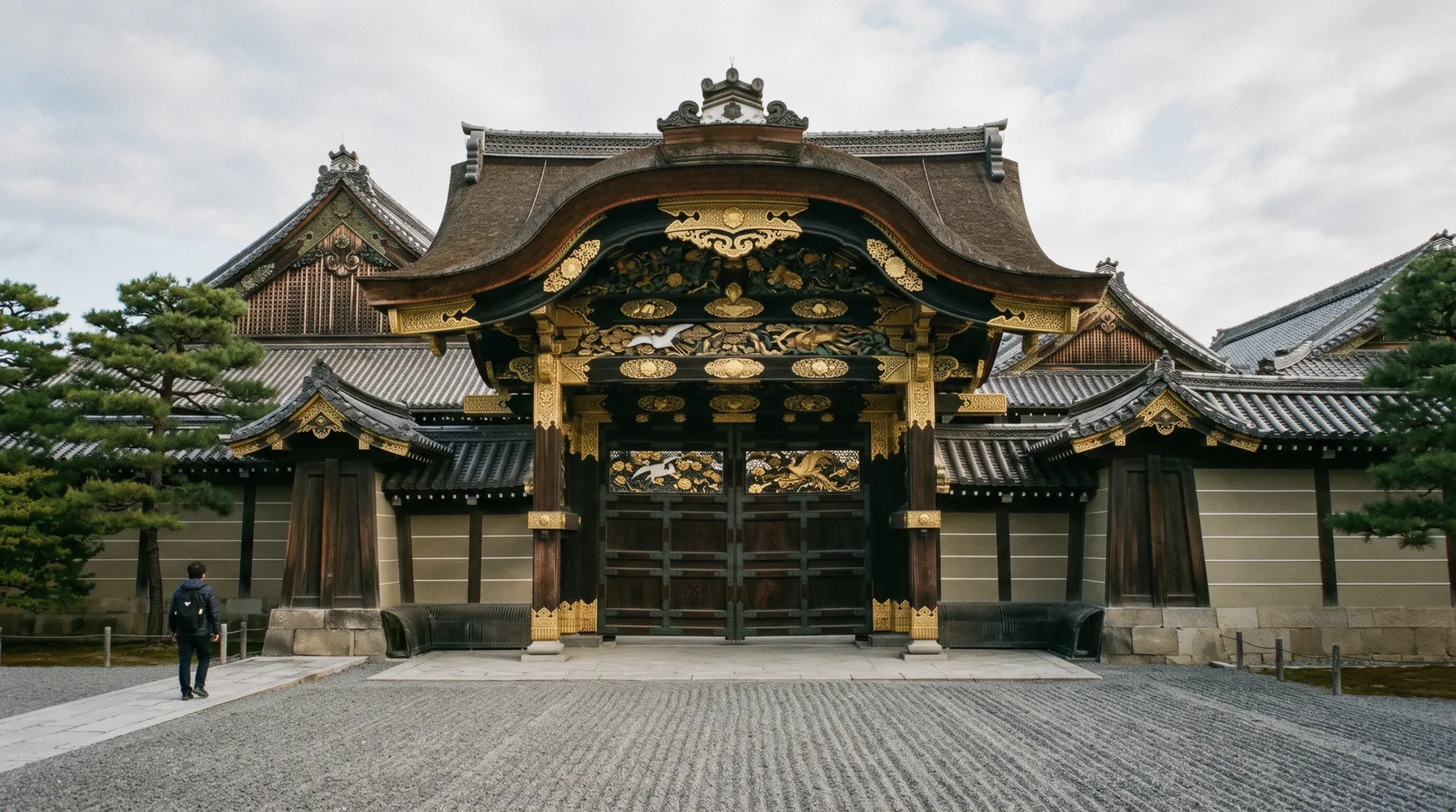 The gilded Kara-mon gate of Nijo Castle under low morning light with the palace roof behind, Kyoto Japan